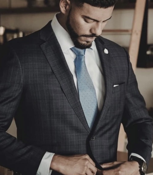 Groomed for Success: young professional in a tailored charcoal suit buttoning his jacket.